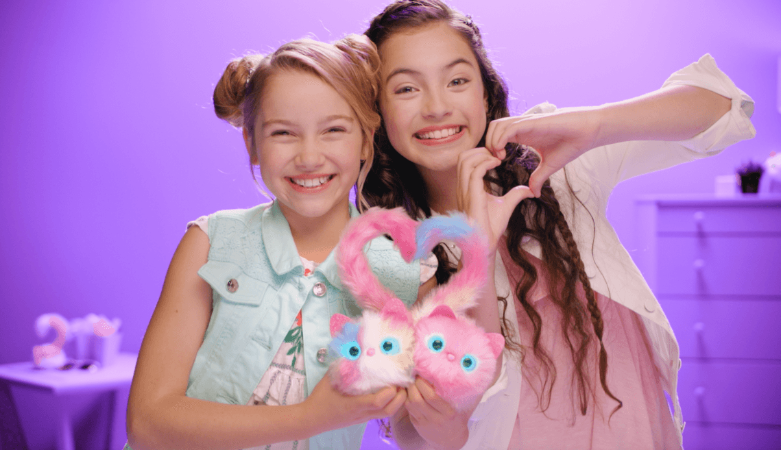 Girls holding Pomsies side by side forming heart with tails of Pomsies.